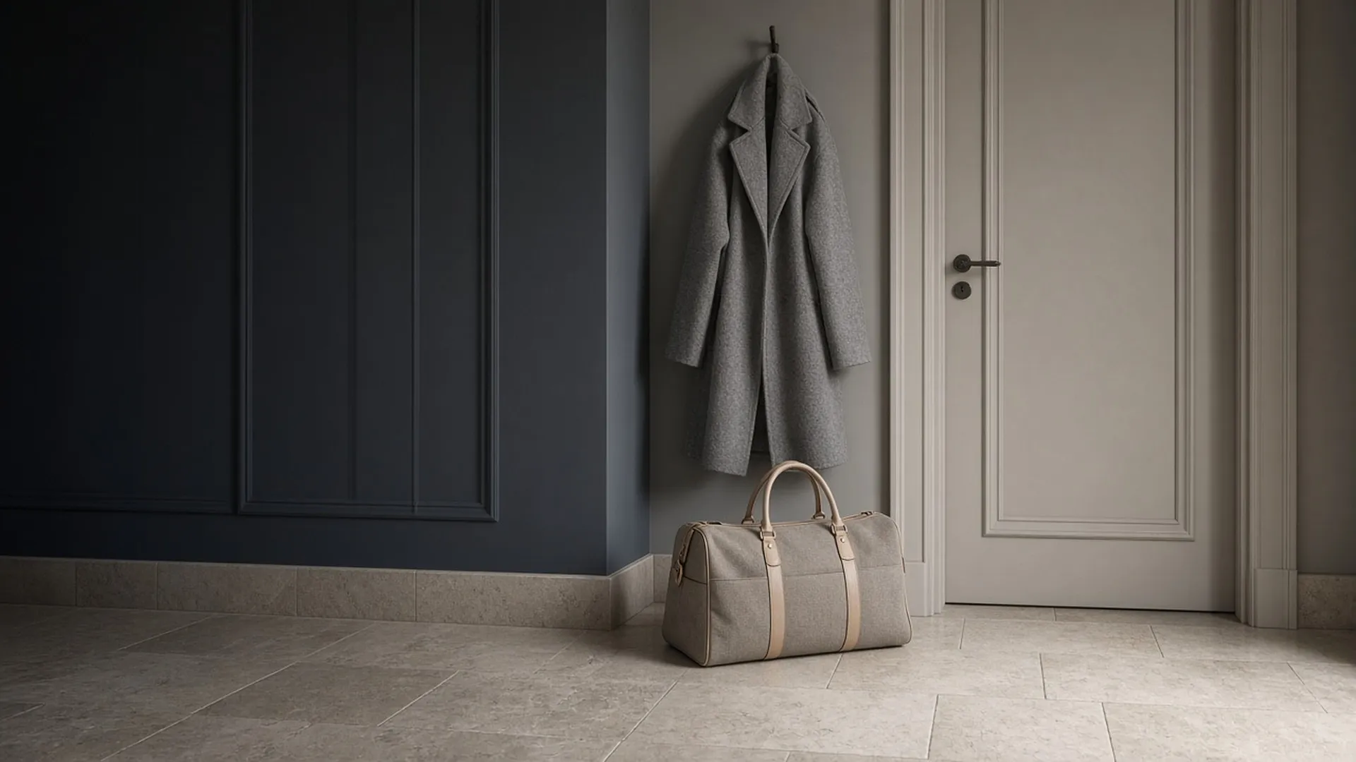 A packed bag waiting by a closed front door below a coat on a hook