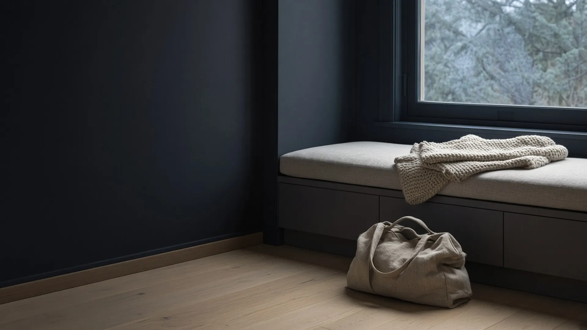 A quiet window seat with a folded throw and a packed bag on the floor