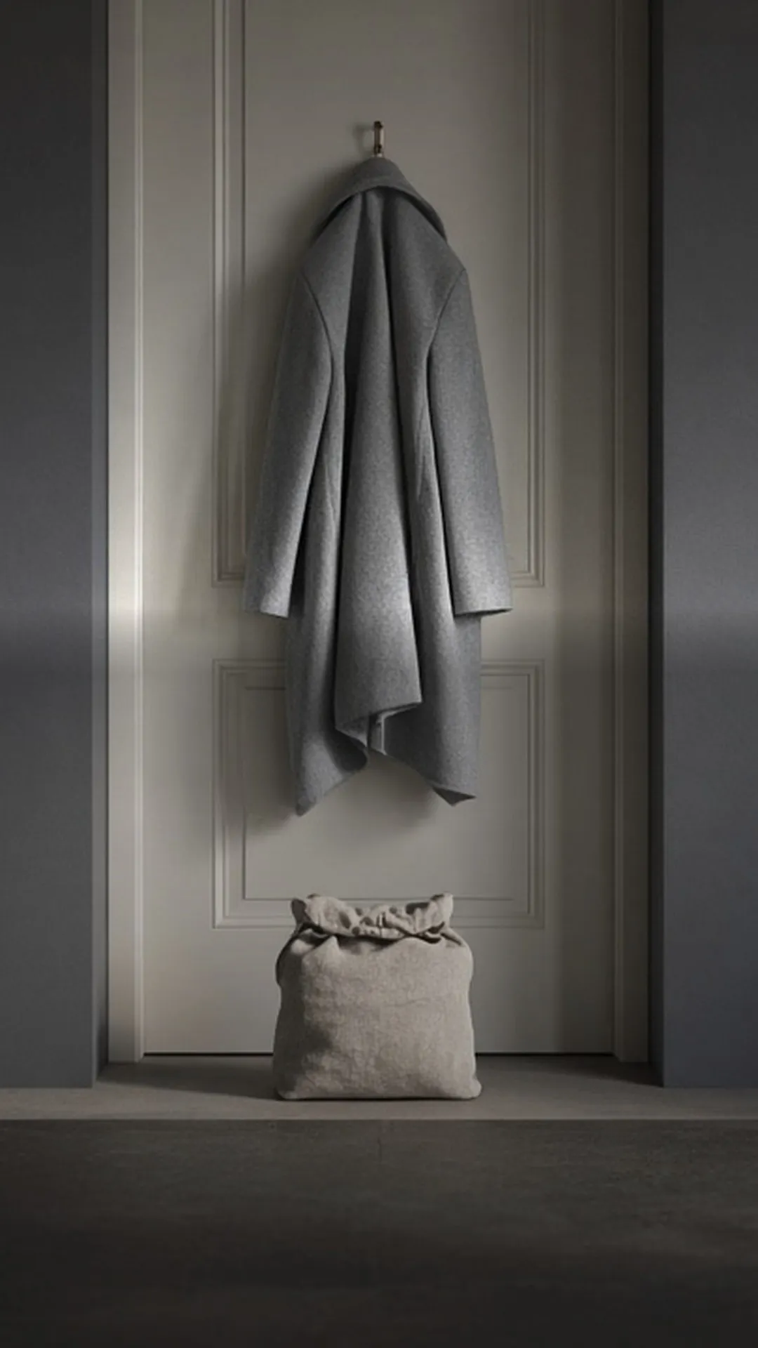 A packed bag waiting by a closed front door below a coat on a hook