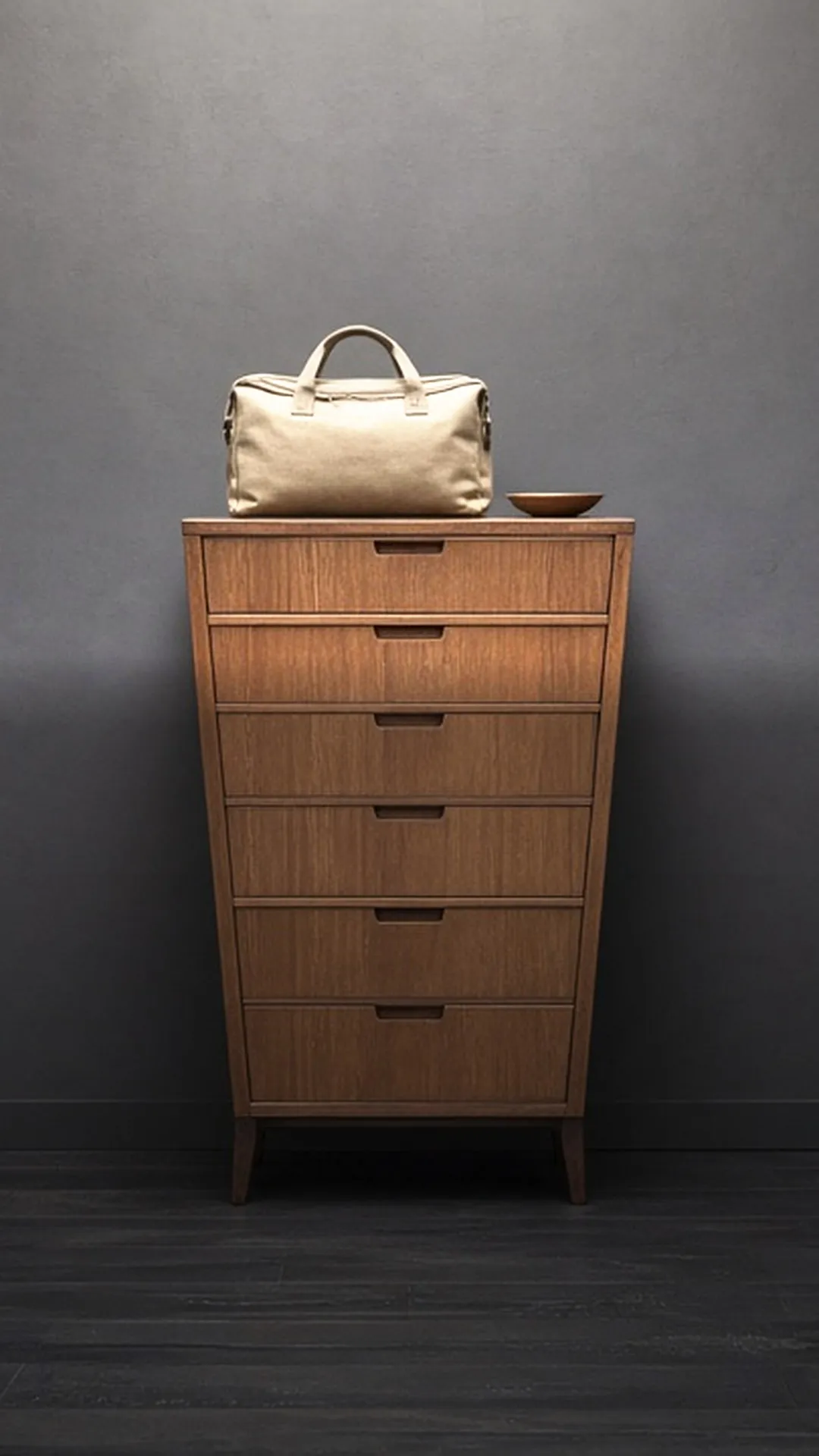 A zipped soft bag on a wooden dresser beside a small empty wooden dish